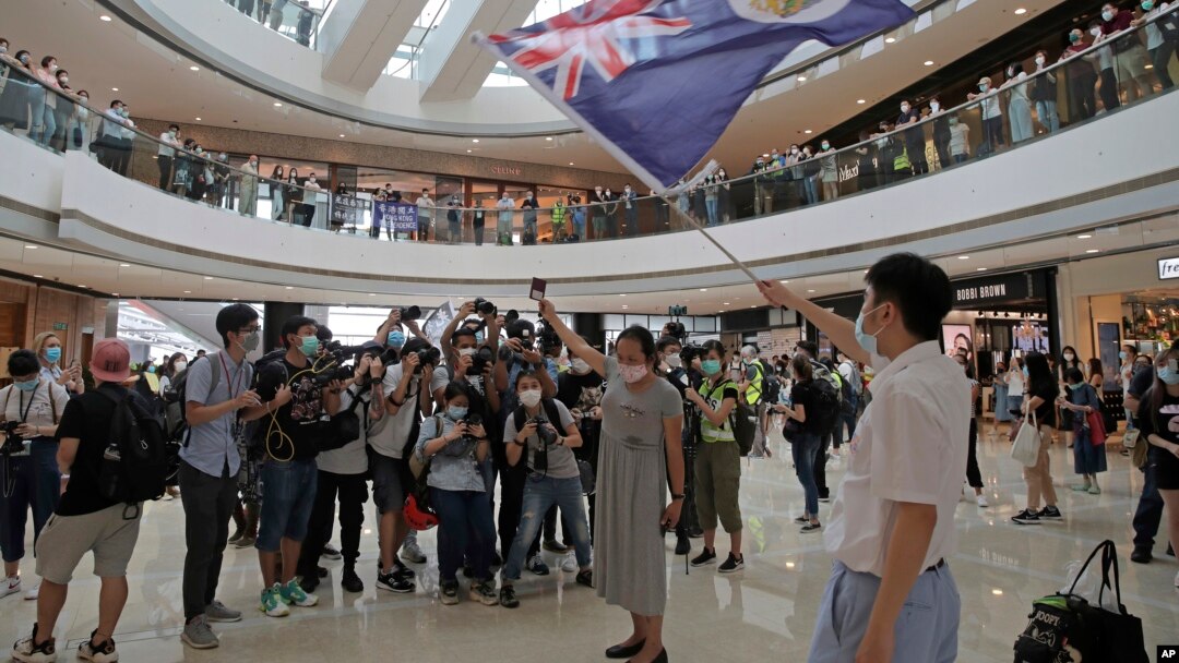 Para pengunjuk rasa menunjukkan Paspor Nasional Inggris (Luar Negeri) dan bendera Hong Kong di sebuah pusat perbelanjaan dalam unjuk rasa memprotes Undang-Undang Keamanan China, di Hong Kong, 29 Mei 2020.