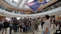 Para pengunjuk rasa memegang paspor Inggris (Luar Negeri) dan bendera kolonial Hong Kong di sebuah pusat perbelanjaan dalam aksi protes terhadap undang-undang keamanan nasional China di Hong Kong, Jumat, 29 Mei 2020.