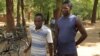 Eric Aniva (left) in a striped gold shirt smokes a cigarette before sentencing started on Tuesday at Nsanje magistrate court. (L. Masina for VOA)