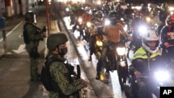 Police officers inspect motorcycle riders at a checkpoint during a stricter lockdown as a precaution against the spread of the coronavirus at the outskirts of Marikina City, Philippines, on Aug. 6, 2021.