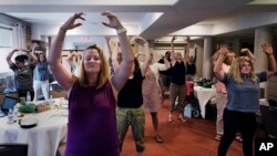 Instructor Emily Daniels, left, raises her arms while leading a workshop helping teachers find a balance in their curriculum while coping with stress and burnout in the classroom on August 2, 2022 in Concord, New Hampshire. (AP Photo/Charles Krupa)