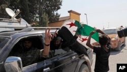 Members of Turkey-backed Syrian National Army (former FSA) flash the V-sign as they drive back to Turkey near the border between Turkey and Syria, in Akcakale, Sanliurfa province, southeastern Turkey, Oct. 9, 2019. 