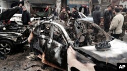 In this photo released by the Syrian official news agency SANA, Syrian citizens and security forces gather next to damaged cars at the scene where explosion hit a commercial street, in the costal town of Jableh, Syria, Jan. 5, 2017.