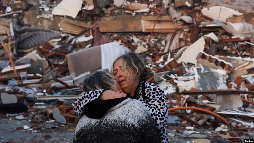 Dua orang perempuan saling berpelukan di dekat puing-puing setelah gempa bumi menghantam Hatay, Turki, 7 Februari 2023. (Foto: REUTERS/Umit Bektas)