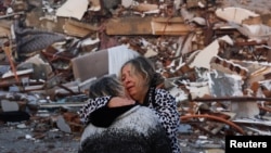 Dua orang perempuan saling berpelukan di dekat puing-puing setelah gempa bumi menghantam Hatay, Turki, 7 Februari 2023. (Foto: REUTERS/Umit Bektas)