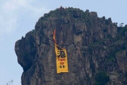 Firefighters remove a yellow banner with the words "Fight for Hong Kong" in Chinese and English from the Lion Rock mountain, June 16, 2019. Hong Kong was bracing Sunday for another massive protest over an unpopular extradition bill.