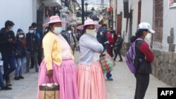 Women wear face masks amid concerns over the spread of the COVID-19 coronavirus as they line up in front of a bank in Puno, Peru, on Oct. 5, 2020.