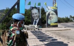 FILE - A United Nations peacekeeper (UNIFIL) stands near a poster depicting Lebanon's Hezbollah leader Sayyed Hassan Nasrallah, in Adaisseh village, near the Lebanese-Israeli border, Lebanon, Aug. 7, 2020.