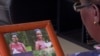 In this image taken from video, Margaret Ntale, whose three student daughters are stranded in Wuhan, looks at photographs of her children as she speaks to The Associated Press at her house in Kampala, Uganda, Feb. 27, 2020.