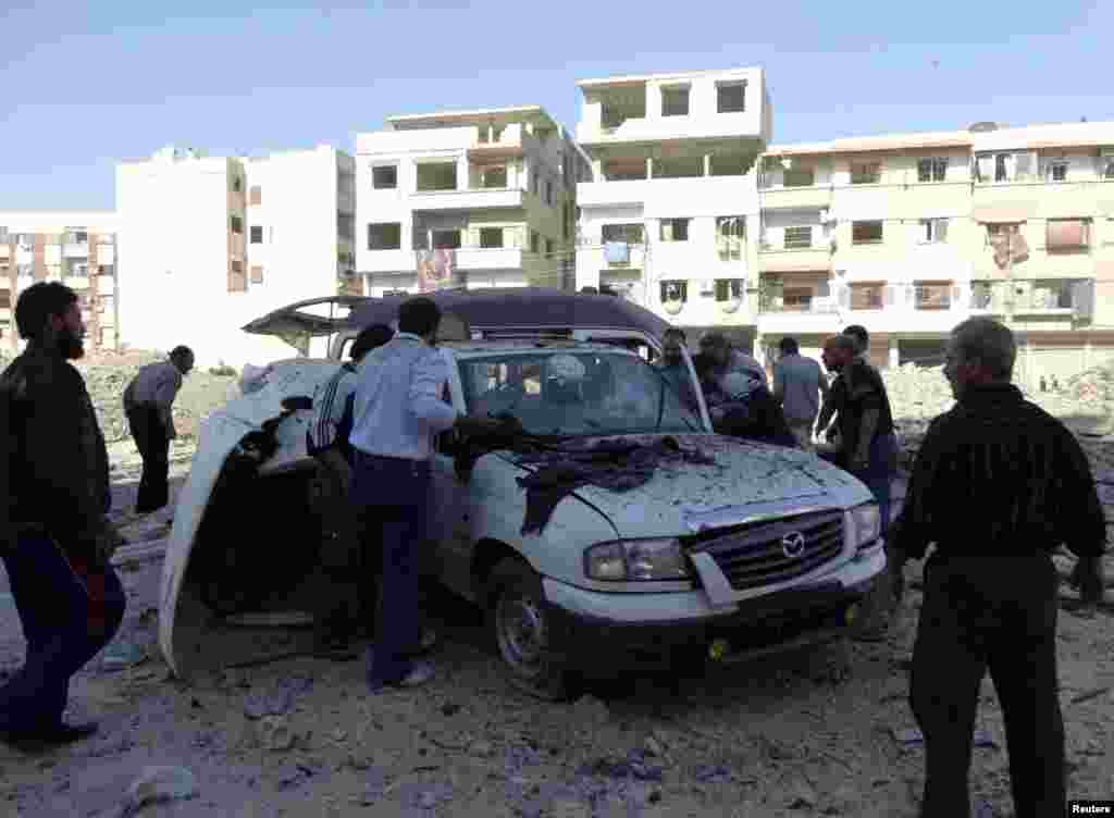 Men search for casualties inside a damaged car after what activists say was an air strike by forces loyal to Syrian President Bashar al-Assad, Hammouriyeh, Syria, Oct. 7, 2013.