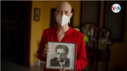 Cristhian Tinoco, hija del exvicecanciller Victor Hugo Tinoco, sostiene una fotografía de su padre, detenido hace una semana en Nicaragua. [Foto:  VOA]