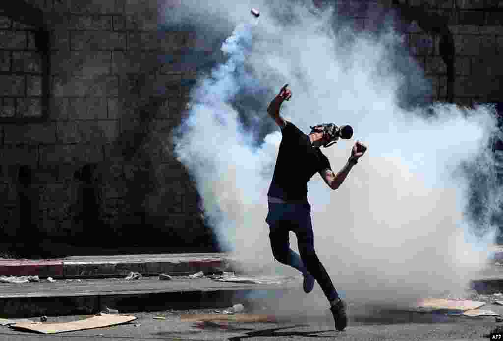 요르단강 서안 도시 나블루스에서 유대인 정착촌 건설에 반대하는 팔레스타인 시위대가 이스라엘 군인들이 발사한 최루탄을 집어 던지고 있다.