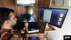 A member of the Kurdistan Centre for Arts and Culture, scans the pages of an old book, as part of an effort to digitise historic Kurdish volumes and manuscripts, in the northern Iraqi city of Dohuk on Feb. 13, 2024.