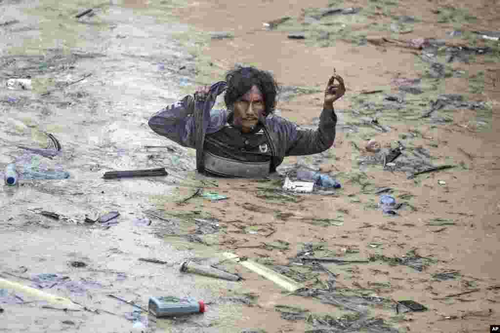 A man wades through flood water following heavy downpours in Medan, North Sumatra, Indonesia.