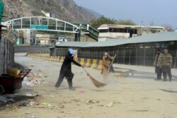 Workers clean a street near the closed Pakistan-Afghanistan border amid concerns over the spread of COVID-19, in Torkham some 54 kms from Peshawar, March 16, 2020.