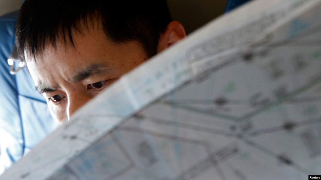 FILE - A Japan Coast Guard officer studies a map onboard their Gulfstream V Jet aircraft, customized for search and rescue operations, as they search for the missing Malaysia Airlines MH370 plane over the waters of the South China Sea, March 15, 2014.