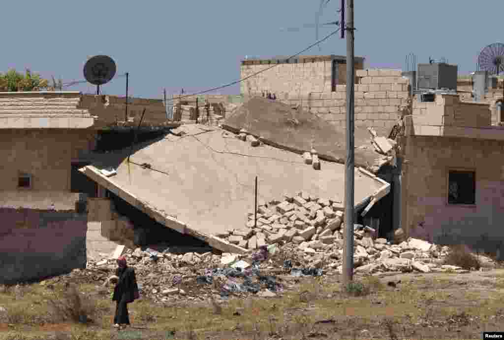 A man walks past a damaged building in the Idlib countryside, Syria.