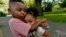 Zavion Guzman hugs his sister Jazzmyn, June 30, 2021, in Belleville, NJ. Lunisol Guzman adopted the two as babies but died last year from COVID-19 along with her partner at the start of the violent first wave of the pandemic.