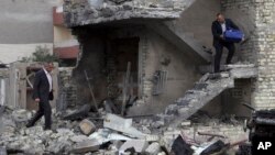 People collect belongings from a damaged building in the aftermath of a car bomb blast in Baghdad, Iraq, Jan 12, 2016. Gunmen stormed into a Baghdad mall on Monday after setting off a car bomb and launching a suicide attack at its entrance, officials said