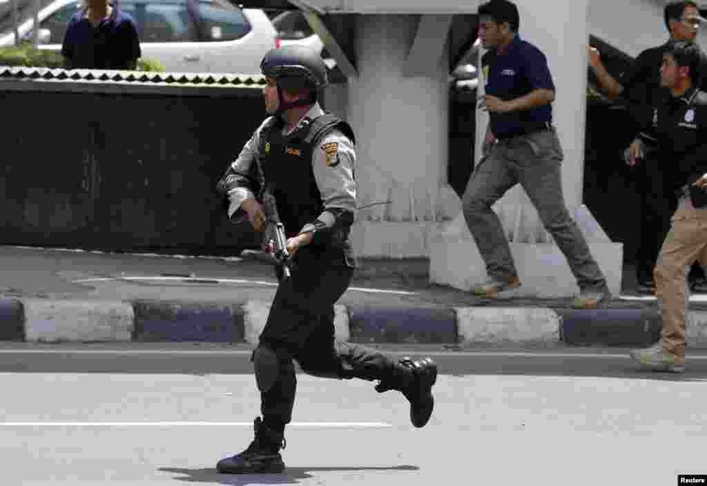 An Indonesian policeman runs near the site of a blast in the center of the Indonesian capital.