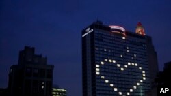 A downtown hotel leaves lights on in vacant room windows to form a heart Friday, March 27, 2020, in Kansas City, Mo.