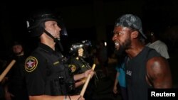 Seorang pria berhadapan dengan seorang polisi di luar Departemen Kepolisian Kenosha di Kenosha, Wisconsin, AS, selama protes menyusul penembakan polisi terhadap pria kulit hitam, Jacob Blake, 23 Agustus 2020. (Foto: Reuters)