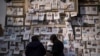 FILE - Women look at photos of people reported to be missing by members of ousted Syrian President Bashar Assad's army, or a pro-government militia, in the Marjeh square in Damascus, Dec. 22, 2024. 