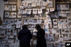 Women look at photos of people reported to be missing by members of ousted Syrian President Bashar al-Assad's army in the Marjeh square in Damascus, Dec. 22, 2024.