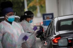 FILE - Medical technicians work at a drive-thru coronavirus testing facility at the Regeneron Pharmaceuticals company's Westchester campus in Tarrytown, New York, September 17, 2020.