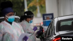 Medical technicians work at a drive-through coronavirus testing facility at the Regeneron Pharmaceuticals company's Westchester campus in Tarrytown, N.Y., Sept. 17, 2020.