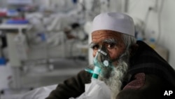 An Afghan patient infected with COVID-19 sits on a bed in the intensive care unit of the Afghan Japan Communicable Disease Hospital, in Kabul, Afghanistan, Monday, Feb. 7, 2022. (AP Photo/Hussein Malla)