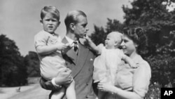 FILE - Britain's Queen Elizabeth II, then Princess Elizabeth, stands with her husband Prince Philip, the Duke of Edinburgh, and their children Prince Charles and Princess Anne at Clarence House, the royal couple's London residence, August 1951.