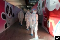 FILE - Workers wearing protective gear walk through the airport ahead of the 2022 Winter Olympics, Feb. 1, 2022, in Beijing.