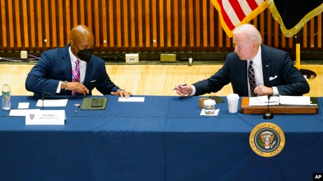 President Joe Biden hands a note to New York City Mayor Eric Adams during a discussion on gun violence strategies, at police headquarters, in New York, Feb. 3, 2022.