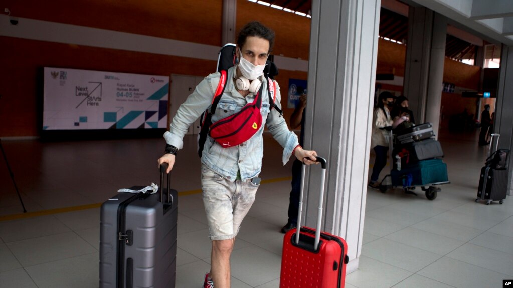 A Russian tourist carries his luggage upon his arrival at Bali's international airport, Indonesia on Friday, Feb. 4, 2022. (AP Photo/Firdia Lisnawati)