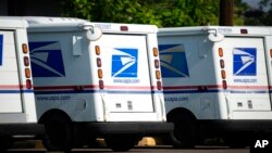 FILE - United States Postal Service delivery vans sit outside a post office in Greeley, Colo., July 26, 2021. 