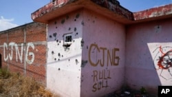 FILE - The letters 'CJNG' for the group’s formal name, Jalisco New Generation Cartel, are scrawled on the facade of an abandoned home, in El Limoncito, in the Michoacan state of Mexico, Oct. 30, 2021.