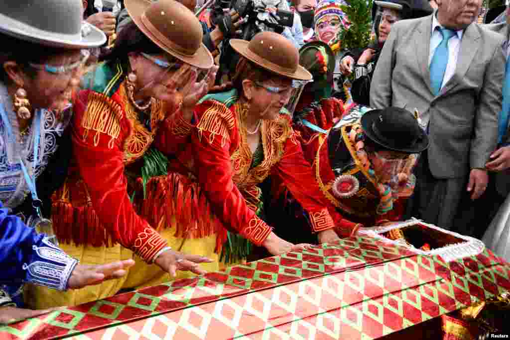 Cholitas, or Andean women, look at a man dressed as &quot;Pepino&quot;, a carnival character, before they revive him as part of a ceremony to kick off carnival season in La Paz, Bolivia, Feb. 6, 2022.