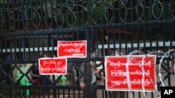 FILE - Prison officers and police gather near the entrance of Insein Prison in Yangon, Myanmar, Oct. 18, 2021. 