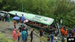 This picture taken in Mangunan, Bantul, Yogyakarta on February 6, 2022 shows residents checking a bus after it crashed killing 13 people and injuring dozens others, police said.