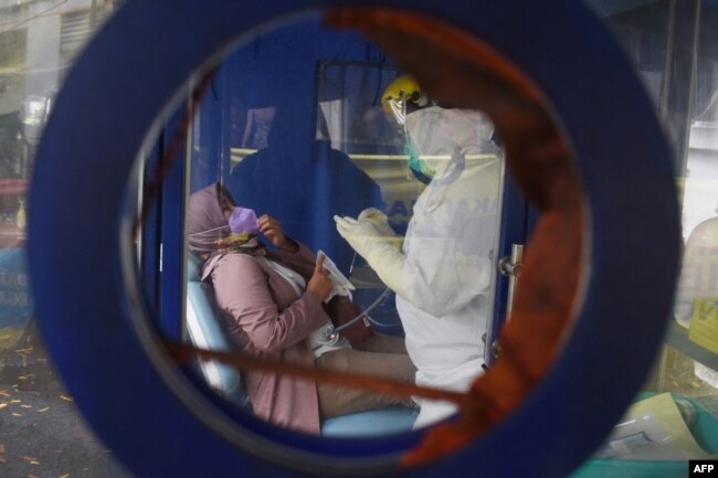 Seorang nakes melakukan pemeriksaan kesehatan sebelum menjalani tes PCR COVID-19 di sebuah sekolah di Bandung, Jawa Barat, 7 Februari 2022. (Timur Matahari/AFP)