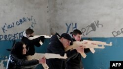 Warga sipil memegang replika senjata Kalashnikov dari kayu, saat mengikuti latihan perang yang diadakan oleh pasukan Ukraina di Kyiv, Minggu 6 Februari 2022. 