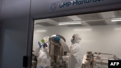 FILE - Employees at the Afrigen biotechnology company and vaccine hub facility work in the manufacturing laboratory in Cape Town, Oct. 5, 2021.