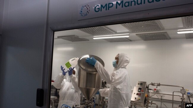 FILE - Employees at the Afrigen biotechnology company and vaccine hub facility work in the manufacturing laboratory in Cape Town, Oct. 5, 2021.