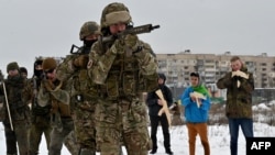 Seorang pelatih militer mengajar warga sipil memegang replika senjata api Kalashnikov dari kayu, dalam pelatihan di pabrik yang sudah tidak terpakai lagi di ibukota Ukraina, Kyiv pada 6 Februari 2022.
