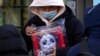 Seorang pria memegang boneka maskot Olimpiade Musim Dingin Beijing Bing Dwen Dwen yang ia beli dari salah satu toko di Beijing, pada 7 Februari 2022. (Foto: AP/Andy Wong)