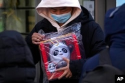 A man holds the Olympic mascot Bing Dwen Dwen doll, which he purchased from a store selling 2022 Winter Olympics memorabilia, in Beijing, Feb. 7, 2022.