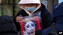 Seorang pria memegang boneka maskot Olimpiade Musim Dingin Beijing Bing Dwen Dwen yang ia beli dari salah satu toko di Beijing, pada 7 Februari 2022. (Foto: AP/Andy Wong)