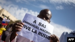 FILE - A man holds up a sign reading 'Down with Emmanuel Macron, long live Russia" during a mass demonstration in Bamako, on Jan. 14, 2022.

