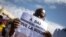 FILE - A man holds up a sign reading 'Down with Emmanuel Macron, long live Russia" during a mass demonstration in Bamako, on Jan. 14, 2022.

